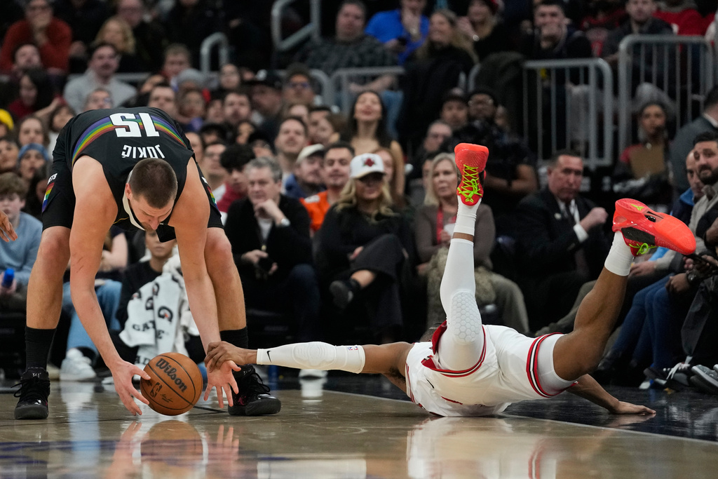 Chicago Bulls forward Isaac Okoro (35), right, slides out of bounds as he fouls Denver Nuggets center Nikola Jokic (15) during the first half of an NBA basketball game Saturday, Feb. 7, 2026, in Chicago. (AP Photo/Erin Hooley)