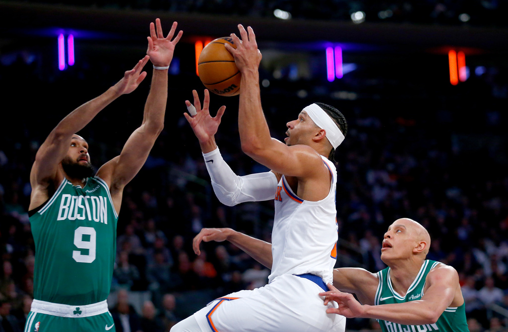 New York Knicks guard Josh Hart, middle, shoots over Boston Celtics guard Derrick White, left, and forward Jordan Walsh during the first half of an NBA basketball game Thursday, April 9, 2026, in New York. (AP Photo/John Munson)