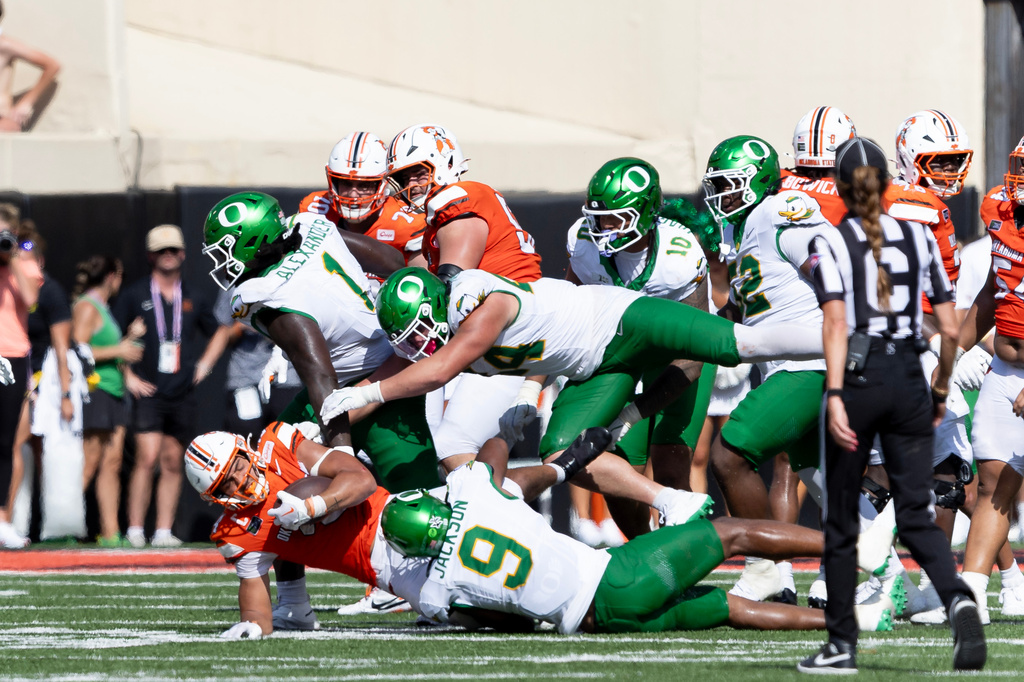 Oklahoma State running back Caleb Hawkins (24) is tackled by Oregon linebacker Devon Jackson (9), linebacker Teitum Tuioti (44) and Bear Alexander in the second half of the NCAA college football game in Stillwater, Okla., Saturday, Sept. 12, 2026. (AP Photo/Mitch Alcala)