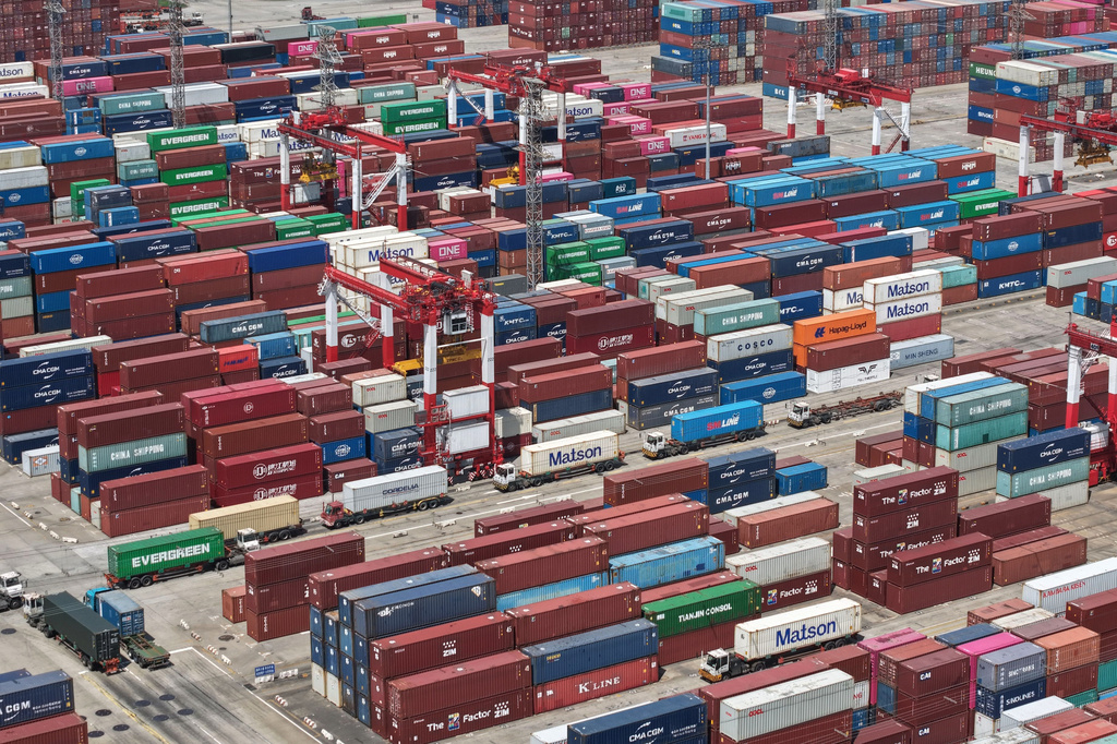 Trucks move past containers stored at a container terminal in Shanghai, China, Tuesday, July 14, 2026. (Chinatopix Via AP)