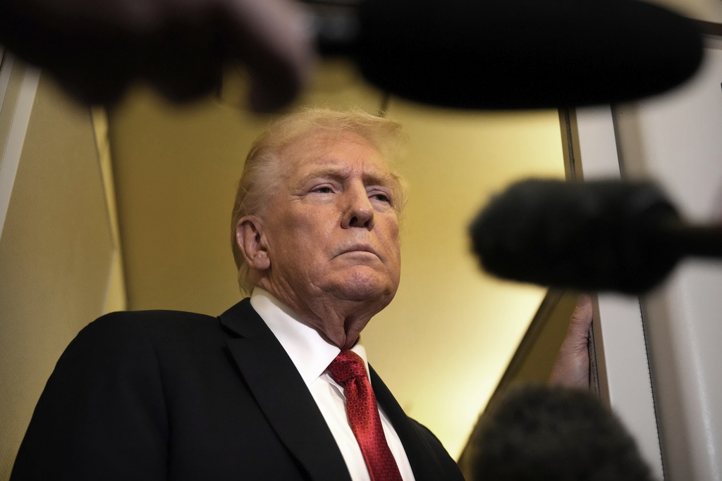 President Donald Trump speaks to reporters aboard Air Force One, Sunday, Oct. 19, 2025, en route to Joint Base Andrews, Md., as he returns from a trip to Florida. (AP Photo/Mark Schiefelbein)