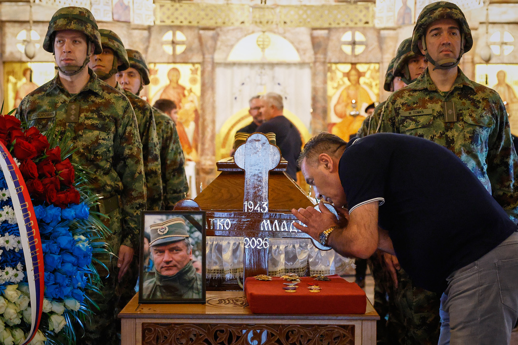 A man touches the cross as Serbian national military servicemen stand around the coffin of the former Bosnian Serb army commander Ratko Mladic, who died last week while serving a life sentence for genocide and other atrocities during the war in Bosnia, at the St. Luka Church, in Belgrade, Serbia, Monday, Sept. 7, 2026. (AP Photo/Marko Drobnjakovic)
