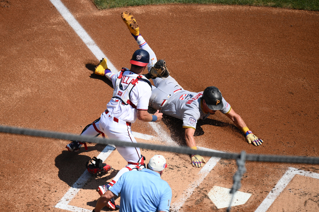 Pittsburgh Pirates' Konnor Griffin, right, steals home to score against Washington Nationals catcher Drew Millas, left, during the first inning of a baseball game, Saturday, July 4, 2026, in Washington. (AP Photo/Nick Wass)