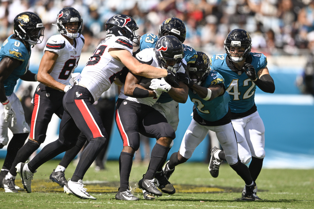 Houston Texans running back Nick Chubb, center, is stopped by Jacksonville Jaguars linebacker Foye Oluokun (23), cornerback Jourdan Lewis (2) and safety Andrew Wingard (42) during the second half of an NFL football game Sunday, Sept. 21, 2025, in Jacksonville, Fla. (AP Photo/Phelan M. Ebenhack)