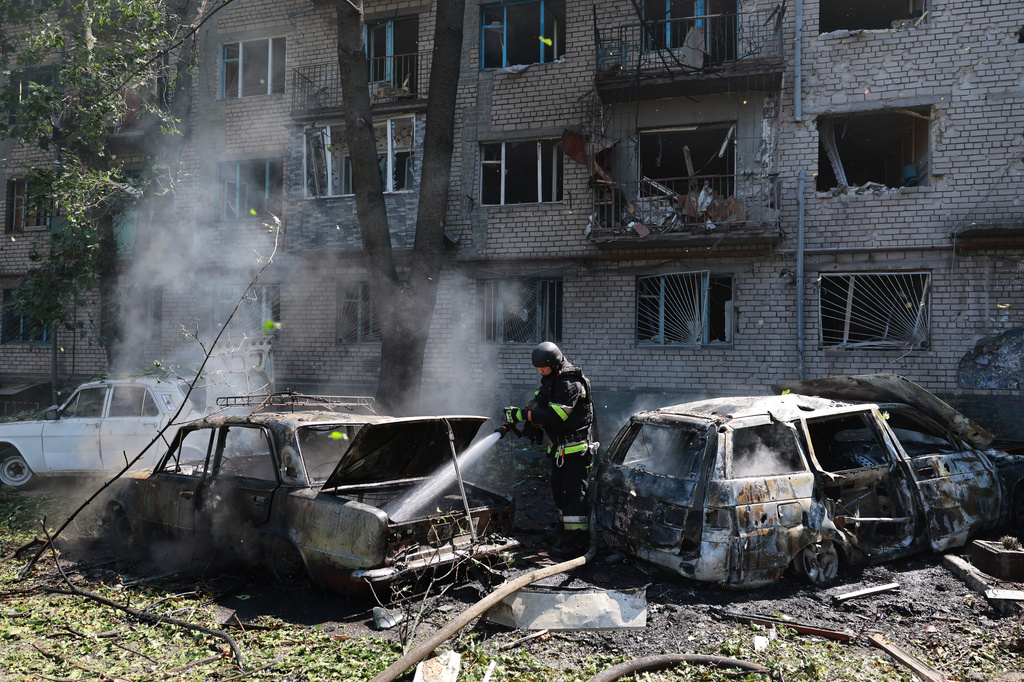 Rescue workers try to put out a fire of a residential building and cars burning after a Russian air guided bomb strike in Zaporizhzhia, Ukraine, Monday, Aug. 10, 2026. (AP Photo/Kateryna Klochko)