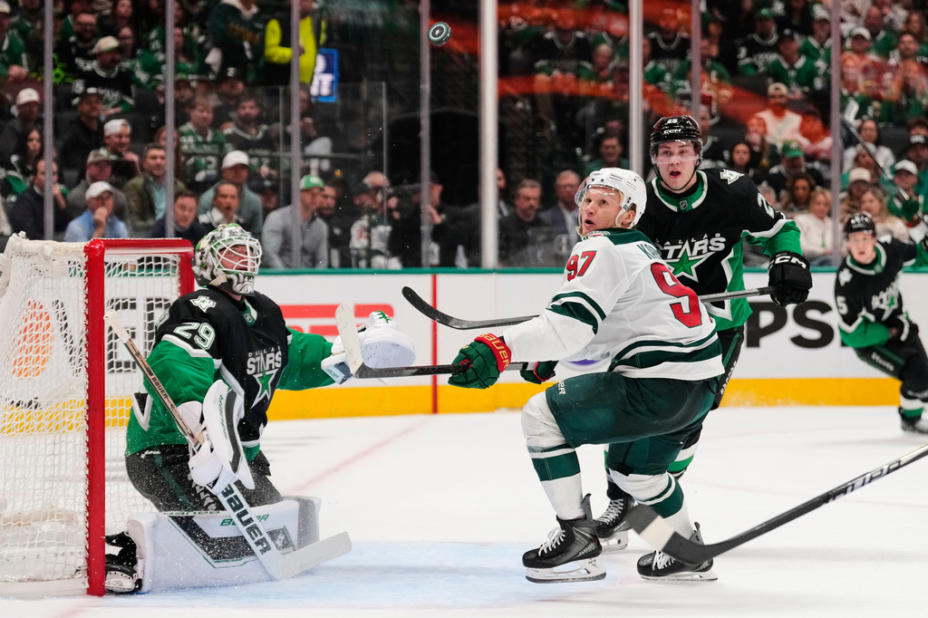 Dallas Stars goaltender Jake Oettinger (29) keeps his eyes on an airborne puck as Minnesota Wild's Kirill Kaprizov (97) pressures the net in the second period of Game 2 of a first-round NHL Stanley Cup playoffs hockey series Monday, April 20, 2026, in Dallas. (AP Photo/Tony Gutierrez)un