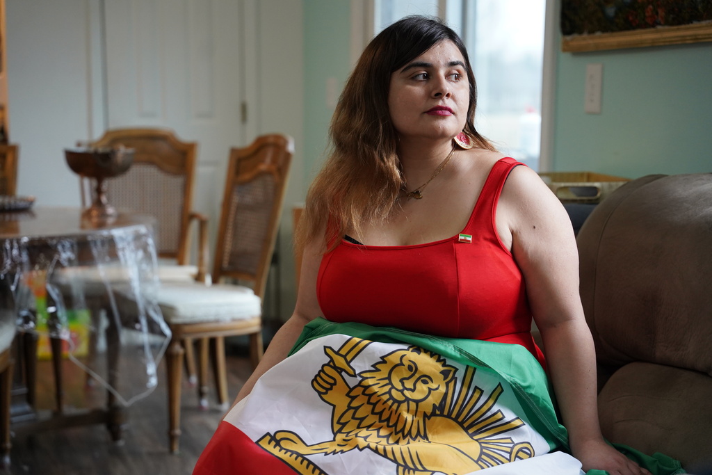 Ava Farhadi, a 33-year-old postdoctoral researcher from Iran, poses for a portrait with an Iranian flag in her home in Lafayette, Ind., Tuesday, March 3, 2026. (AP Photo/Obed Lamy)