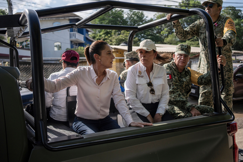 President Claudia Sheinbaum, left, and Veracruz Gov. Rocío Nahle García survey authorities' aid distribution in Poza Rica, Mexico, Sunday, Oct. 12, 2025, after widespread flooding and landslides. (AP Photo/Felix Marquez)