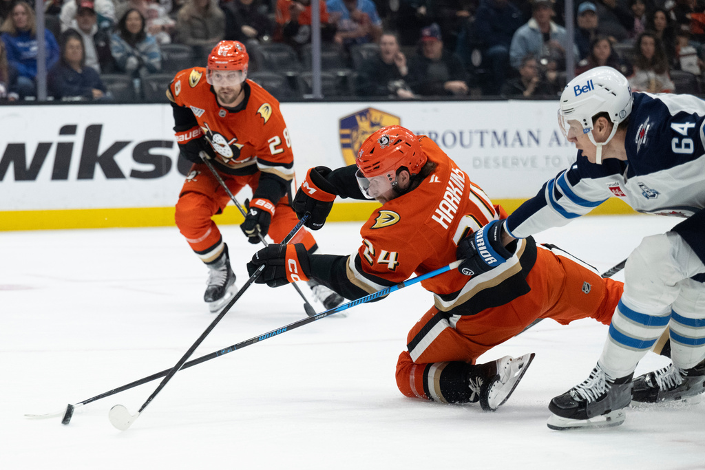 Anaheim Ducks center Jansen Harkins, center, and Winnipeg Jets defenseman Logan Stanley, right, vie for the puck during the first period of an NHL hockey game, Friday, Feb. 27, 2026, in Anaheim, Calif. (AP Photo/Kyusung Gong)