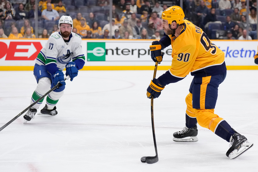 Nashville Predators center Ryan O'Reilly (90) shoots the puck to score a short handed goal past Vancouver Canucks defenseman Filip Hronek (17) during the second period of an NHL hockey game Thursday, Oct. 23, 2025, in Nashville, Tenn. (AP Photo/George Walker IV)