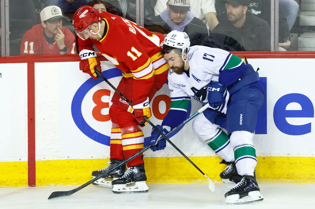 Vancouver Canucks' Filip Hronek (17) runs into Calgary Flames' Mikael Backlund during second period NHL hockey action in Calgary, Alberta, Saturday, March 28, 2026. (Larry MacDougal/The Canadian Press via AP)