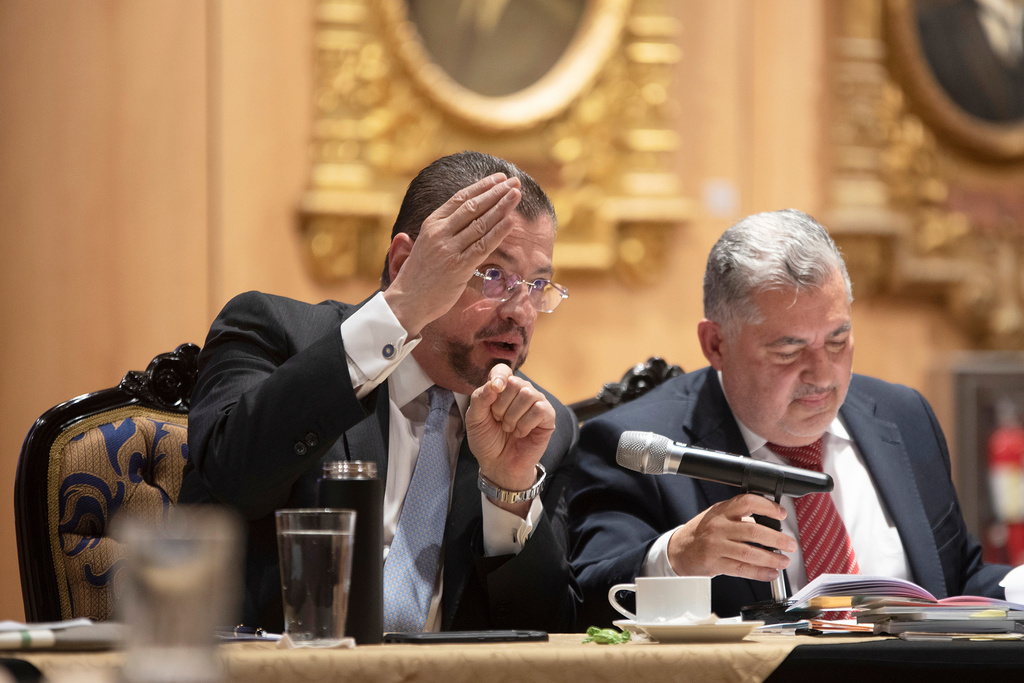 Costa Rican President Rodrigo Chaves speaks next to lawyer Jose Miguel Villalobos before a legislative committee considering a request from the Supreme Court to lift his immunity so he can stand trial on corruption charges in San Jose, Costa Rica, Friday, Aug. 22, 2025. (AP Photo/Jose Diaz)