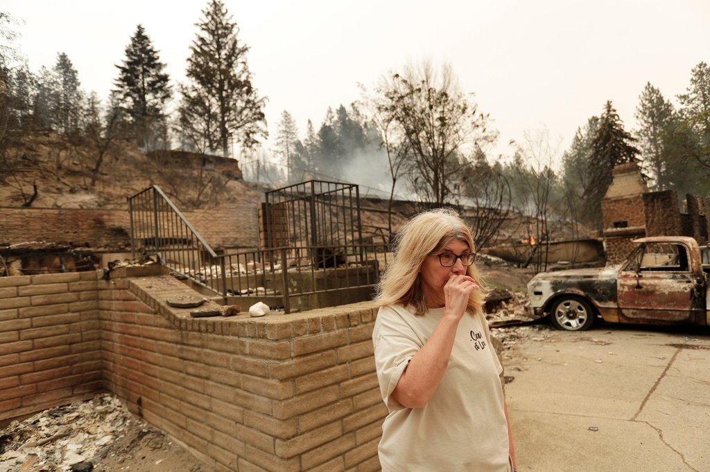 Kimberley Sather stands at the duplex she rents on W. Indian Trail Rd. after it burned in a wildfire in Spokane, Wash., Sunday, Aug. 2, 2026. (AP Photo/Young Kwak)