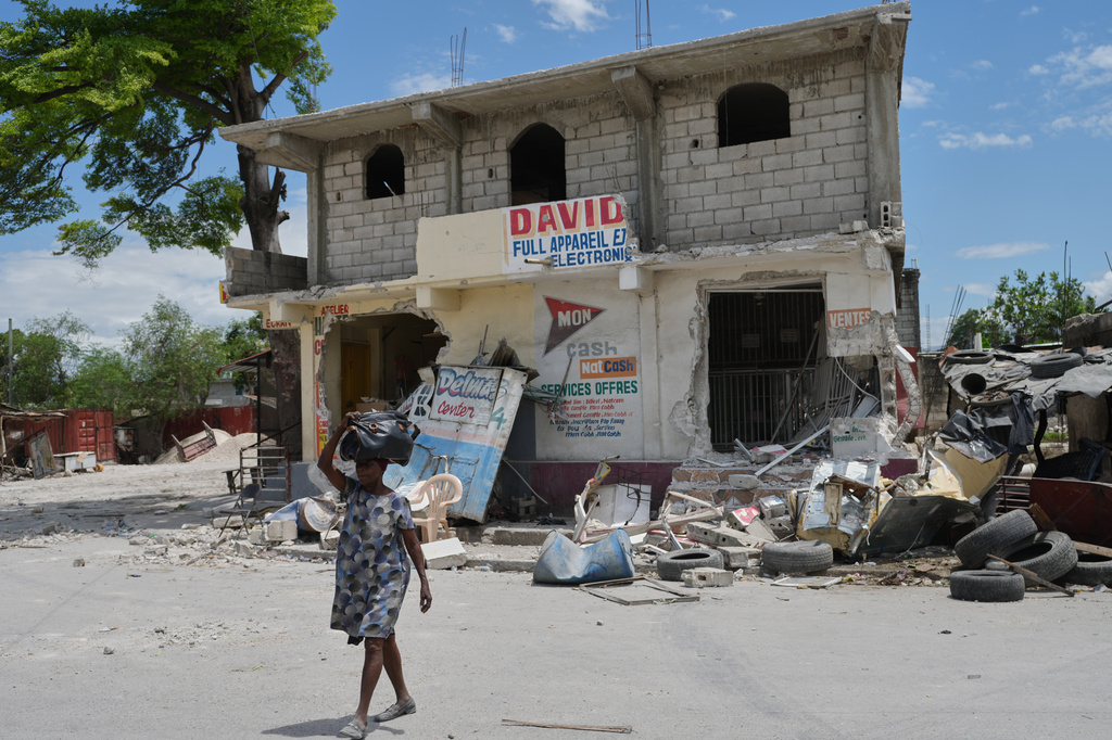 A woman leaves her home to escape clashes between armed gangs in the Cité Soleil neighborhood of Port-au-Prince, Haiti, Tuesday, May 12, 2026. (AP Photo/Odelyn Joseph)