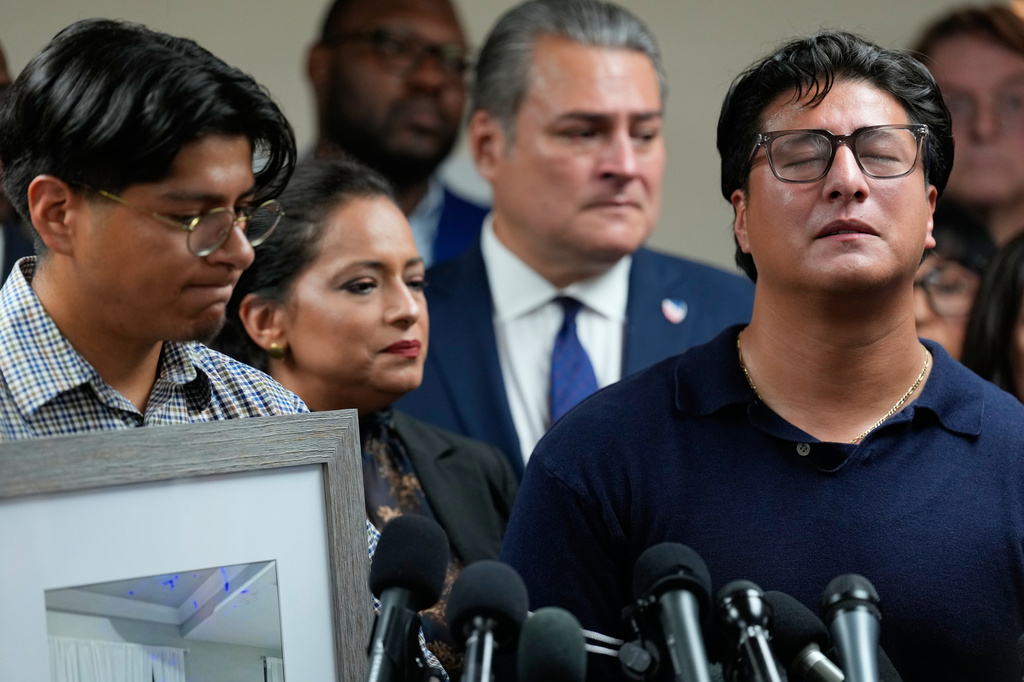 Ronaldo Salgado, son of Lorenzo Salgado Araujo, speaks as his brother, Lorenzo Jr., left, holds family photographs during a news conference Wednesday, July 8, 2026, in Houston. (AP Photo/David J. Phillip)