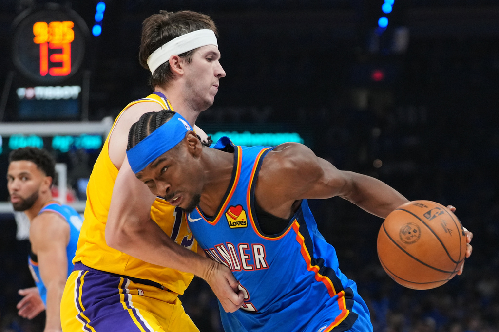 Oklahoma City Thunder guard Shai Gilgeous-Alexander, right, drives to the basket as Los Angeles Lakers guard Austin Reaves, left, defends second half of Game 1 in a second-round NBA basketball playoffs series Tuesday, May 5, 2026 in Oklahoma City. (AP Photo/Kyle Phillips)