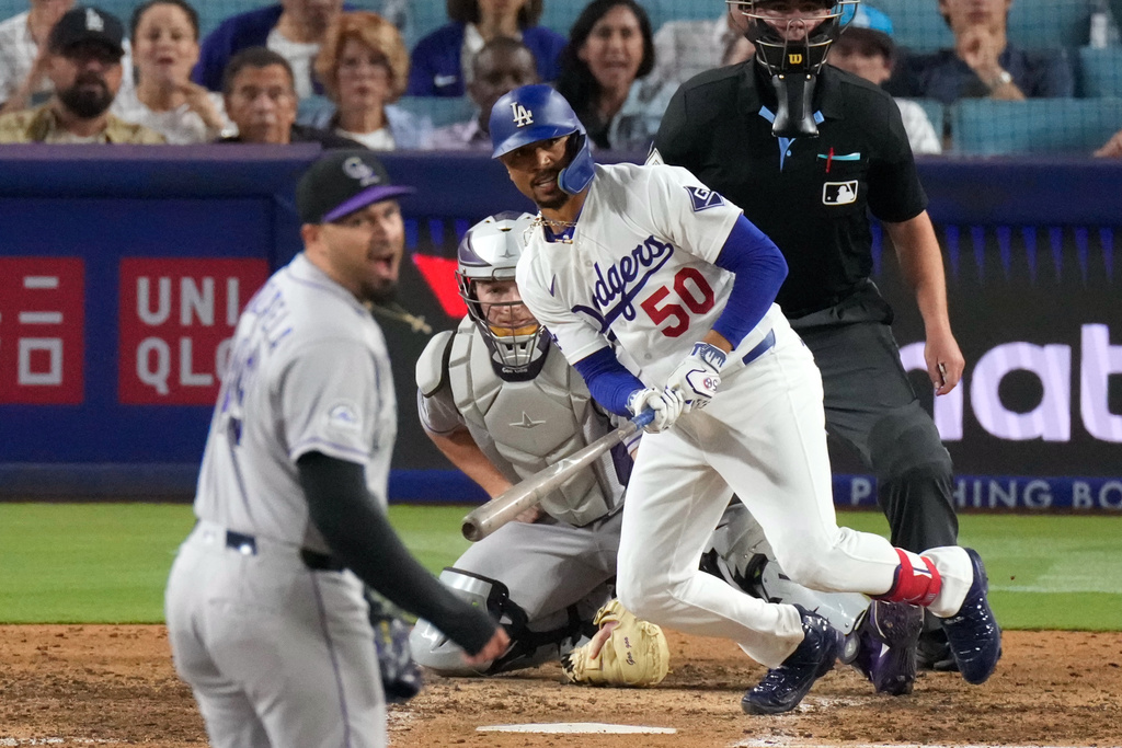Los Angeles Dodgers' Mookie Betts, right, hits an RBI single as Colorado Rockies pitcher Antonio Senzatela, left, reacts during the eighth inning of a baseball Wednesday, July 8, 2026, in Los Angeles. (AP Photo/Mark J. Terrill)