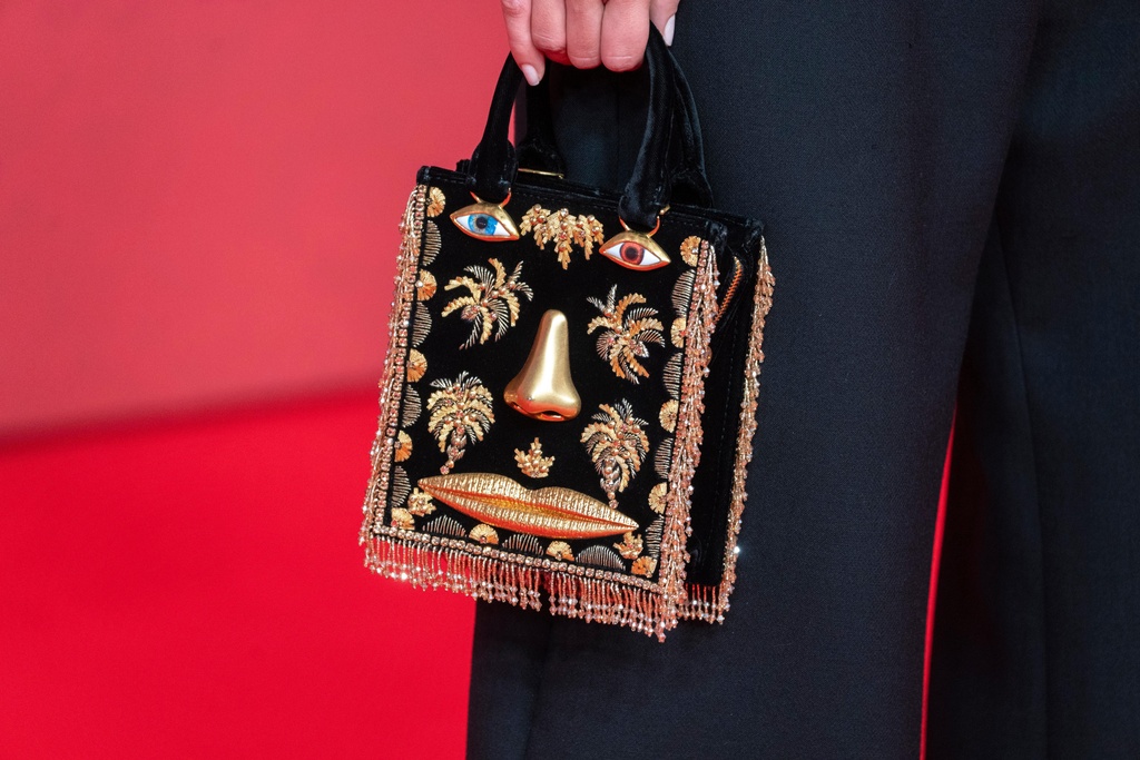An actress holds a Schiaparelli purse while posing for a photo on the red carpet during 22nd Marrakech Film Festival, in Morocco, Tuesday, Dec. 2, 2025. (AP Photo/Mosa'ab Elshamy)