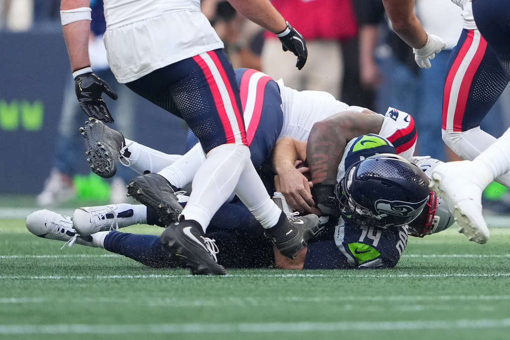 Seattle Seahawks quarterback Sam Darnold, (14) is sacked by New England Patriots linebacker Dre'mont Jones, behind, during the first half an NFL football game, Wednesday, Sept. 9, 2026, in Seattle. (AP Photo/Lindsey Wasson)