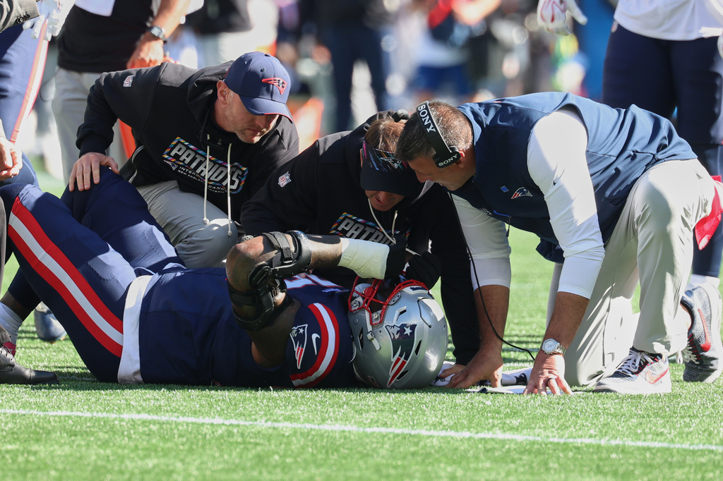 New England Patriots head coach Mike Vrabel, right, checks on offensive tackle Morgan Moses as he lies on the field during the first half of an NFL football game New York Jets in Foxborough, Mass., Sunday, Oct. 18, 2026. (AP Photo/Mark Stockwell)