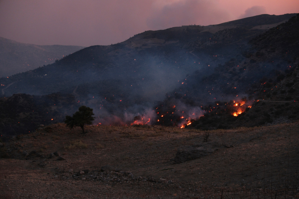 A wildfire burns in the Rethymno region on the southern Greek island of Crete, Wednesday, July 29, 2026, where two firefighters died while battling the blaze. (AP Photo/Giannis Angelakis)
