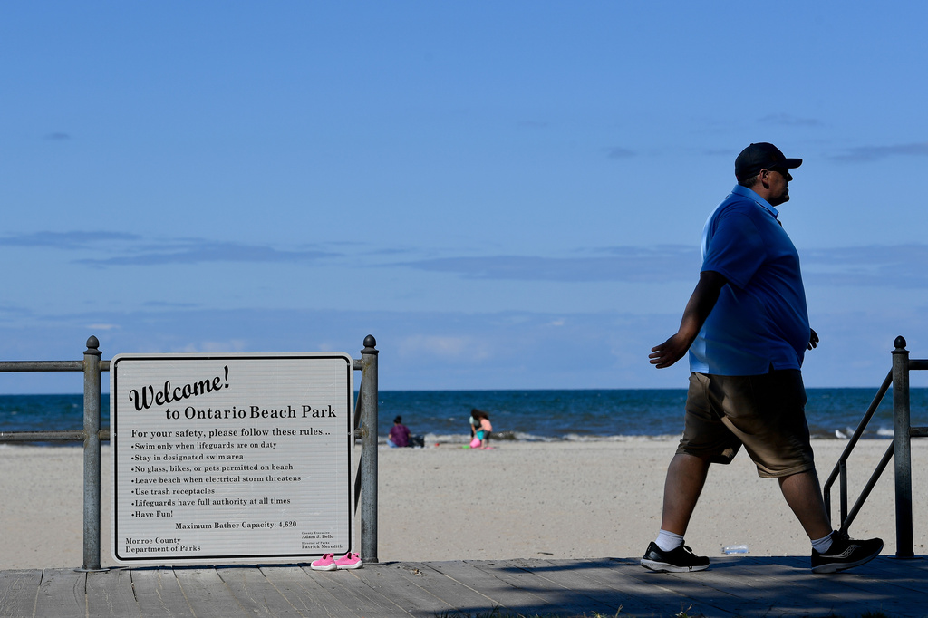 Signs mark the entrance to Ontario Beach Park on the shore of Lake Ontario, Tuesday, Aug. 25, 2026, in Rochester, N.Y. (AP Photo/Adrian Kraus)