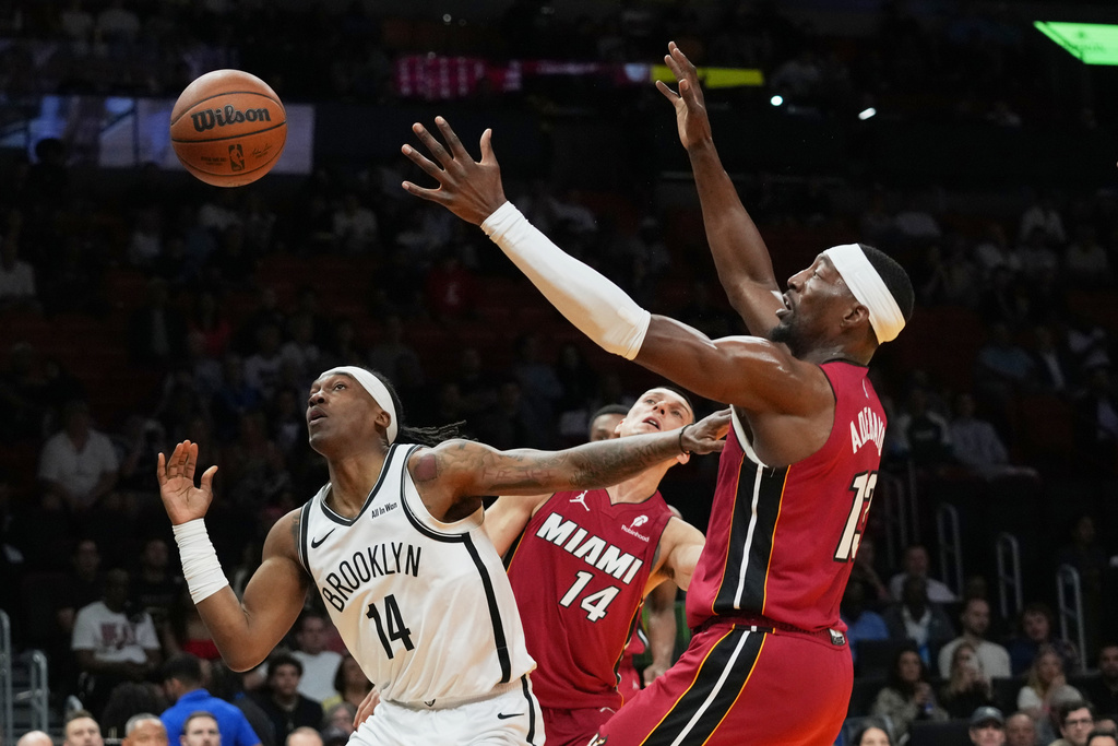 Brooklyn Nets guard Terance Mann (14) loses control of the ball as Miami Heat center Bam Adebayo (13) defends during the first half of an NBA basketball game, Thursday, March 5, 2026, in Miami. (AP Photo/Lynne Sladky)