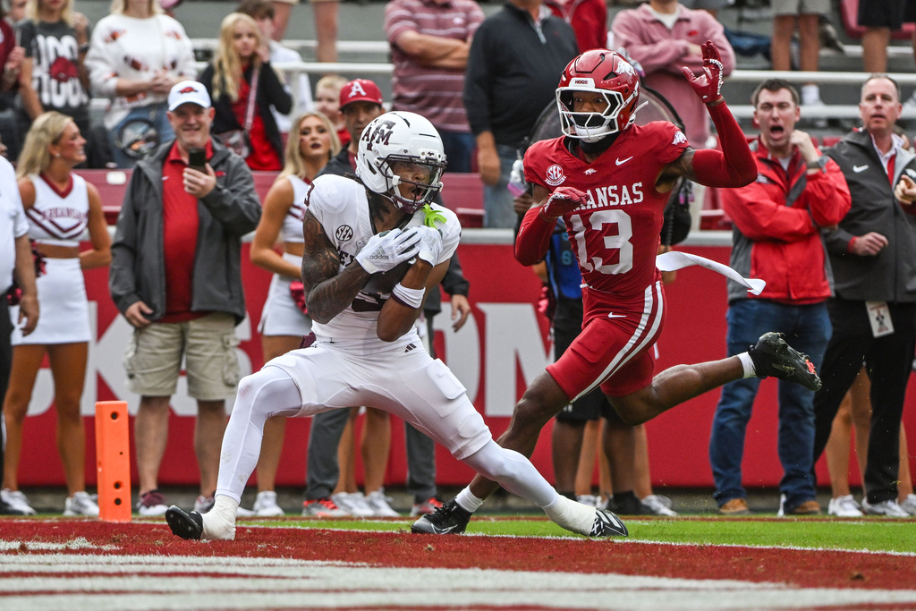 Texas A&M wide receiver Ashton Bethel-Roman (3) catches a touchdown pass in front of Arkansas defensive back Kani Walker (13) during the first half of an NCAA college football game Saturday, Oct. 18, 2025, in Fayetteville, Ark. (AP Photo/Michael Woods)
