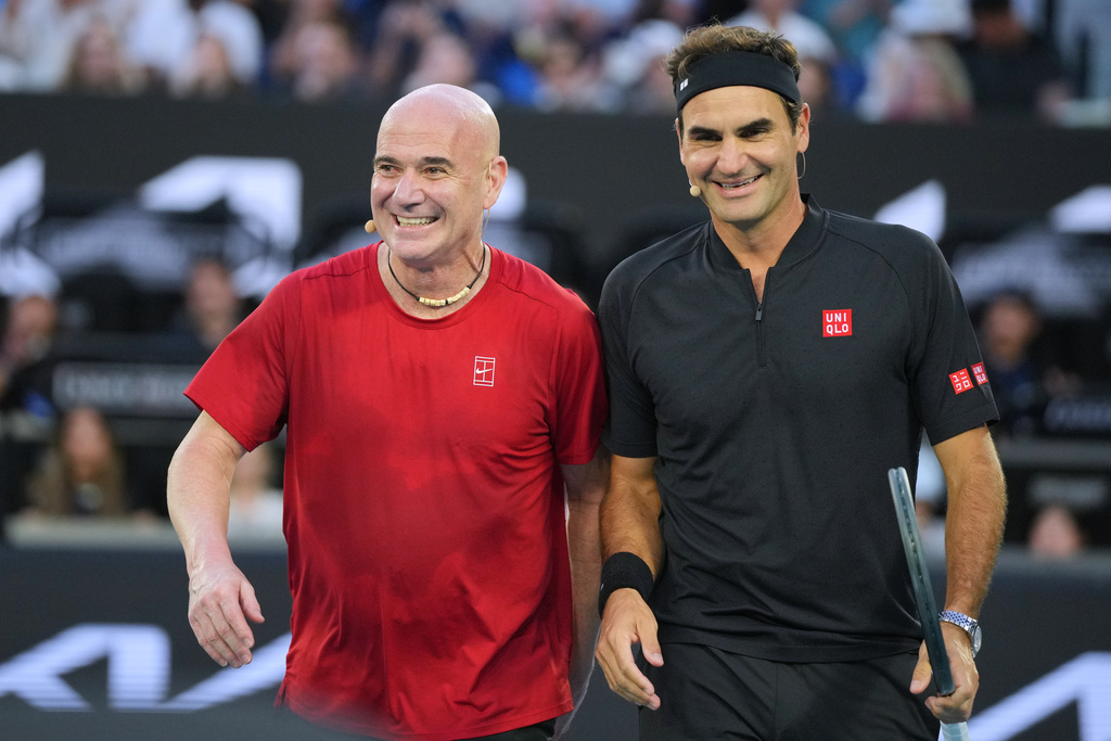 Roger Federer of Switzerland reacts with partner Andre Agassi, left, of the United States in their doubles match against Lleyton Hewitt and Pat Rafter of Australia during the Opening Ceremony for the Australian Open tennis championship in Melbourne, Australia, Saturday, Jan. 17, 2026. (AP Photo/Dita Alangkara)