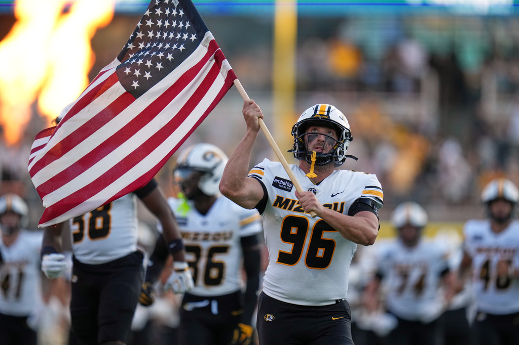 Missouri defensive end Aidan Dubbert carries the United States flag as he runs onto the field before the start of an NCAA college football game against Arkansas-Pine Bluff Thursday, Sept. 3, 2026, in Columbia, Mo. (AP Photo/Jeff Roberson)