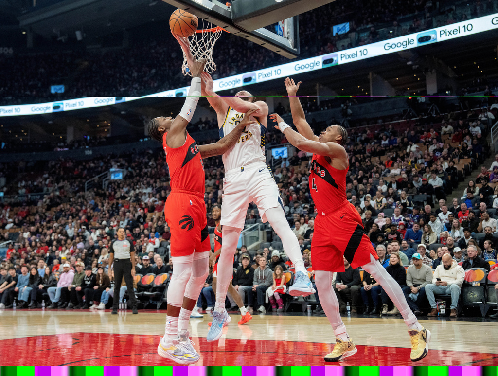 Indiana Pacers centre Jay Huff, center, drives to the hoop between Toronto Raptors forwards R.J. Barrett, left, and Scottie Barnes (4) during first-half NBA basketball game action in Toronto, Sunday Feb. 8, 2026. (Frank Gunn/The Canadian Press via AP)