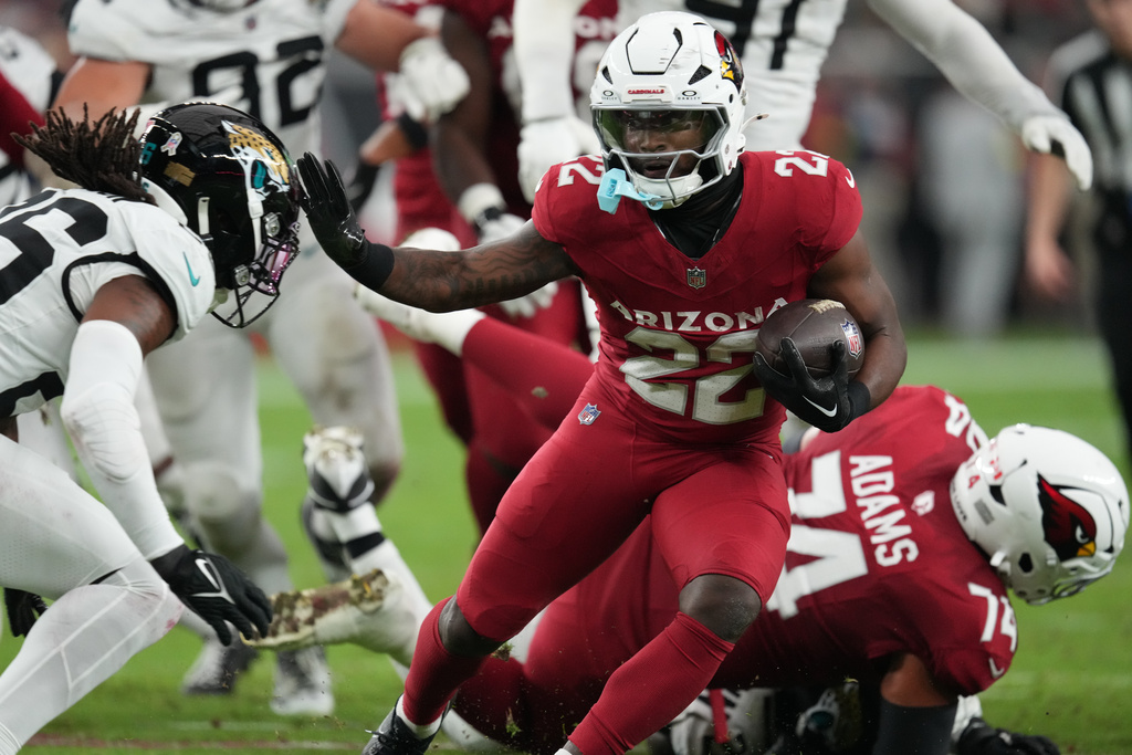 Arizona Cardinals running back Michael Carter (22) runs the ball against Jacksonville Jaguars safety Antonio Johnson (26) during the first half of an NFL football game Sunday, Nov. 23, 2025, in Glendale, Ariz. (AP Photo/Ross D. Franklin)