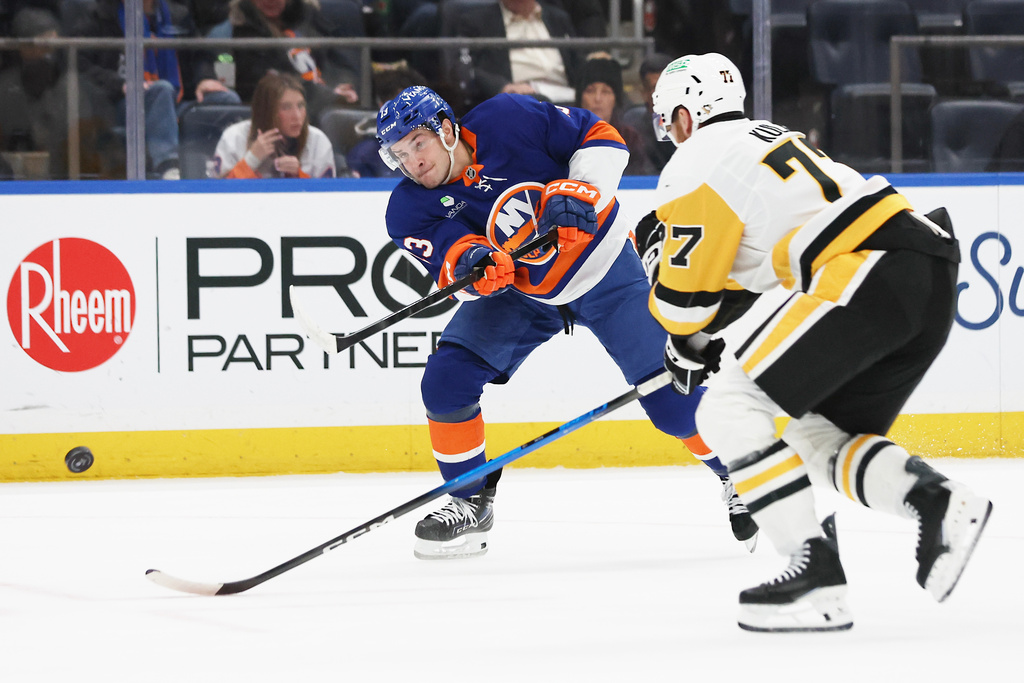 New York Islanders center Mathew Barzal, left, shoots the puck past Pittsburgh Penguins defenseman Brett Kulak (77) during the second period of an NHL hockey game, Tuesday, Feb. 3, 2026, in Elmont, N.Y. (AP Photo/Heather Khalifa)