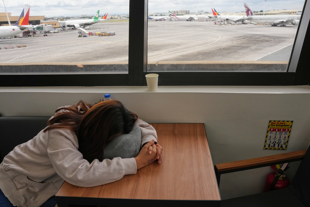 An overseas Filipino worker sleeps as she waits for updates on her cancelled flight to the Middle East at Manila's International Airport, Philippines on Monday, March 2, 2026. (AP Photo/Aaron Favila)