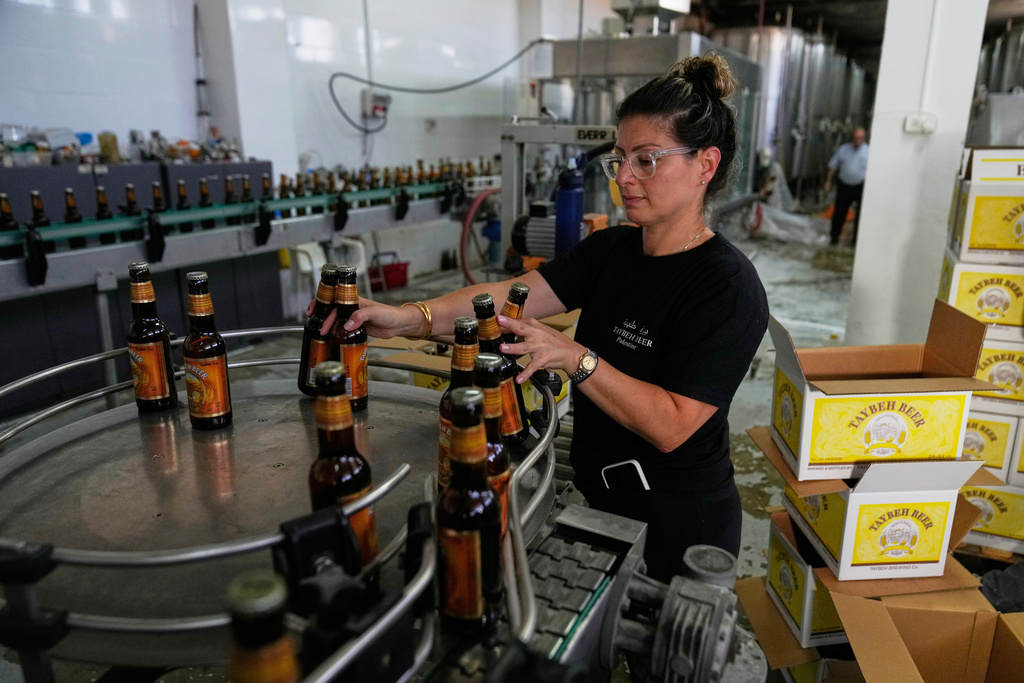 Nadin Khoury, 36, packs Taybeh beer products on a production line of the family's Palestinian Taybeh Brewery Co. in the West Bank town of Taybeh, Saturday, Sept. 6, 2025. (AP Photo/Nasser Nasser)