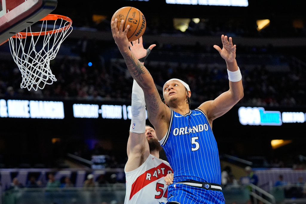 Orlando Magic forward Paolo Banchero (5) shoots over Toronto Raptors forward Sandro Mamukelashvili, left, during the first half of an NBA basketball game, Friday, Jan. 30, 2026, in Orlando, Fla. (AP Photo/John Raoux)