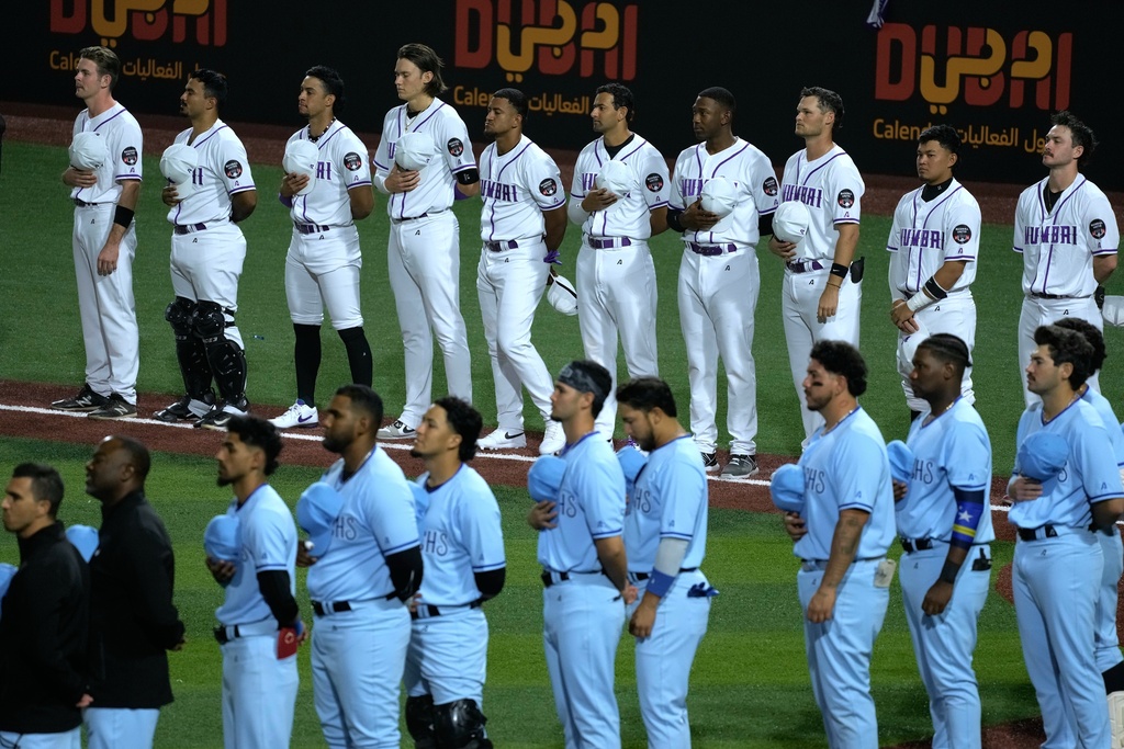Players from the Mumbai and Karachi teams line up ahead of the league's opening baseball game at the new Barry Larkin Field in Ud al-Bayda, on the outskirts of Dubai, United Arab Emirates, Friday, Nov. 14, 2025. (AP Photo/Fatima Shbair)