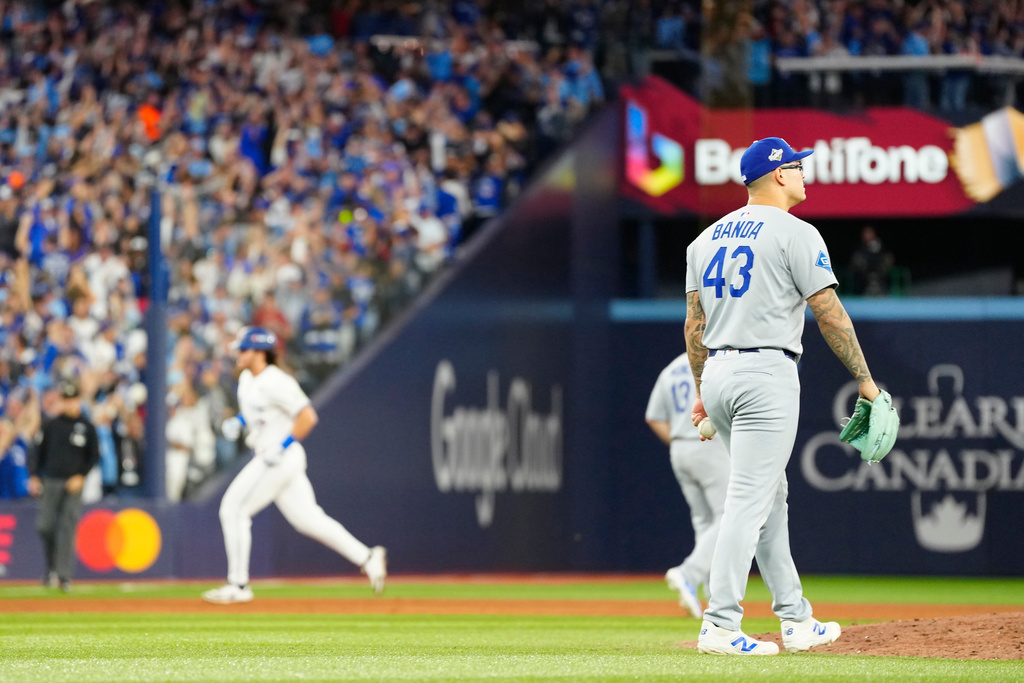 Los Angeles Dodgers pitcher Anthony Banda (43) reacts as Toronto Blue Jays' Addison Barger, back left, rounds the bases after hitting a grand slam during the sixth inning of Game 1 of baseball's World Series in Toronto, Friday, Oct. 24, 2025. (Frank Gunn/The Canadian Press via AP)