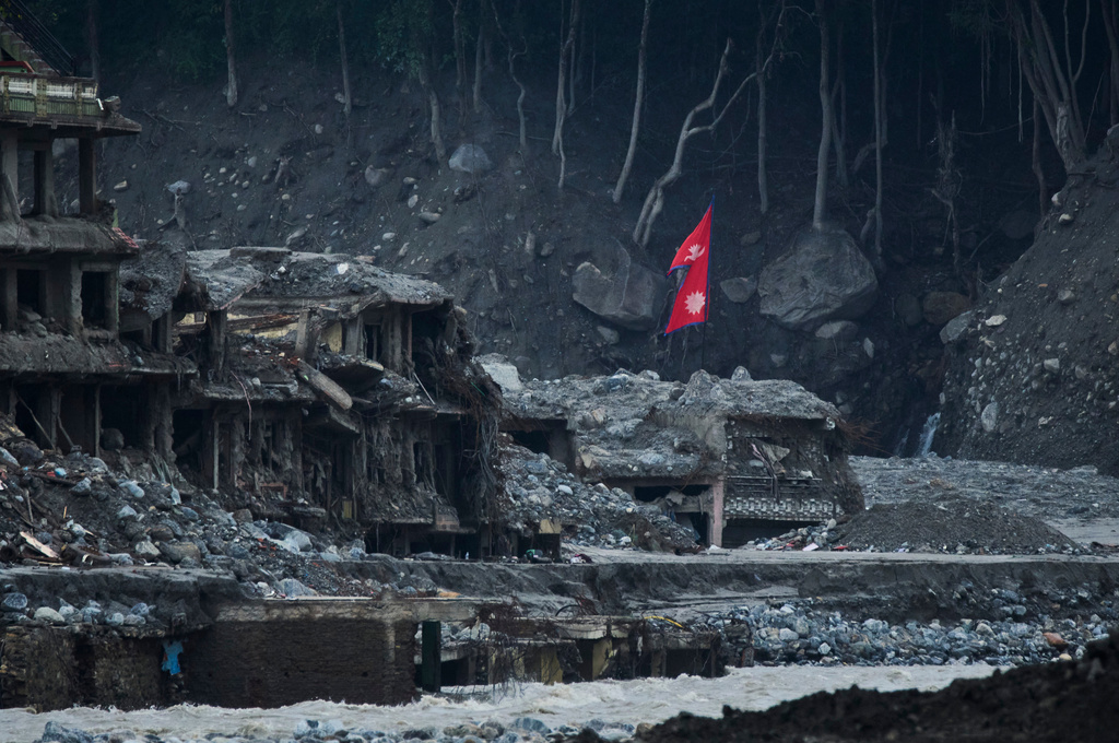 A Nepalese flag flies amid houses damaged by flash floods along the banks of the Trishuli River in Dunge, in Nepal's Nuwakot district, Wednesday, Sept. 23, 2026. (AP Photo/Niranjan Shrestha)