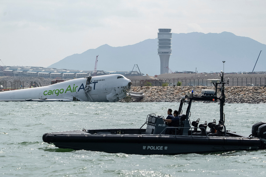 Police officers on a boat patrol near a cargo aircraft that skidded off a Hong Kong runway on Monday, Oct. 20, 2025. (AP Photo/Chan Long Hei)