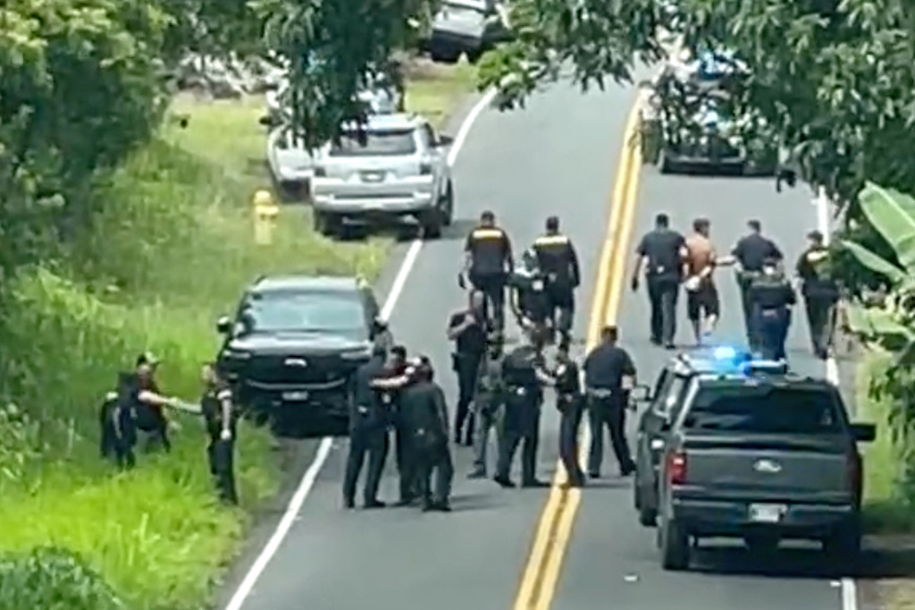 Police arrest a man accused of multiple killings, right, on Thursday, May 28, 2026, in Kaimu, Hawaii. (Deborah Davis via AP)