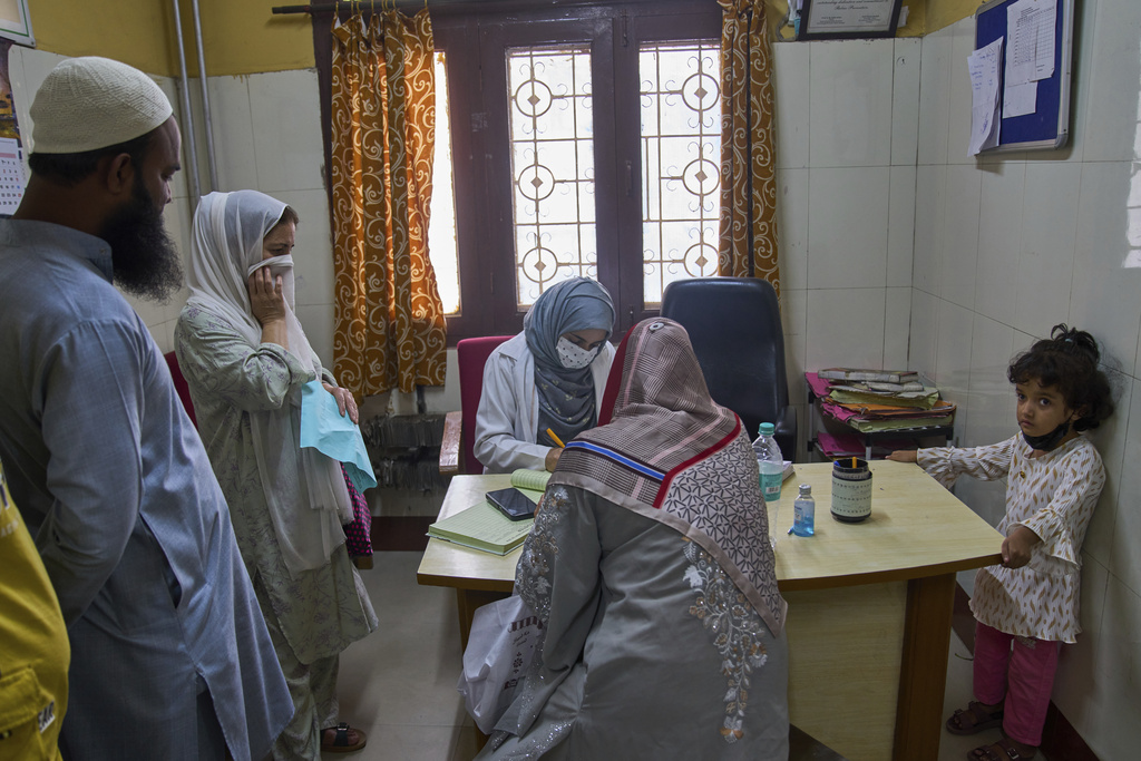 Rehmat Ashraf, 6, right, who was attacked by a dog outside her house, looks on as Insha Rehman, center in grey scarf, records patient details inside the anti-rabies clinic at a hospital in Srinagar, Indian controlled Kashmir, Thursday, Sept. 18, 2025. (AP Photo/Dar Yasin)