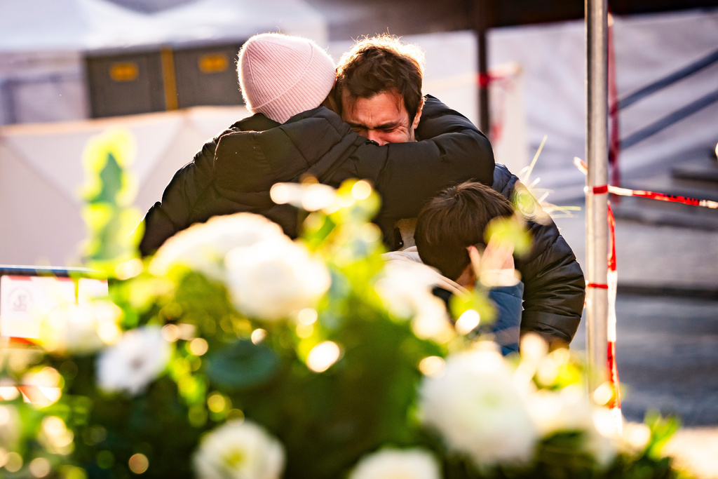 People cry at the scene after a fire broke out at the "Le Constellation" bar and lounge during New Year's celebration, in Crans-Montana, Switzerland, Thursday, Jan. 1, 2026. (Jean-Christophe Bott/Keystone via AP)
