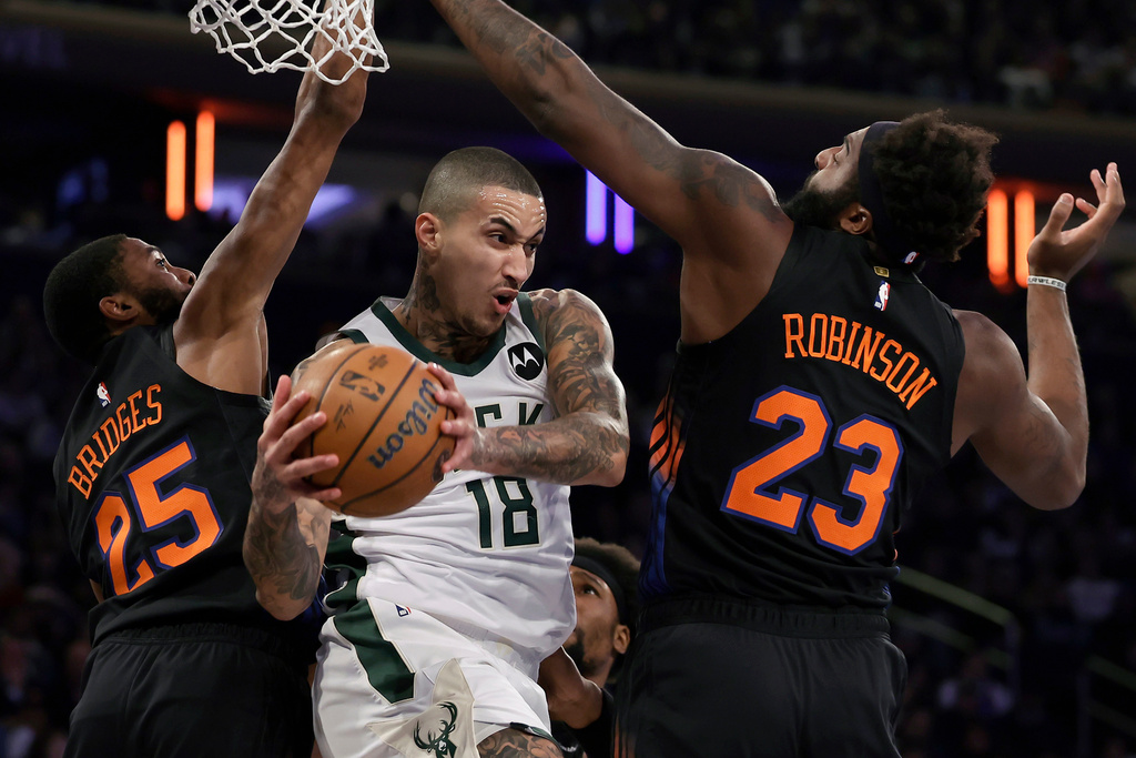 Milwaukee Bucks forward Kyle Kuzma (18) drives between New York Knicks center Mitchell Robinson (23) and Mikal Bridges (25) during the first half of an NBA basketball game, Friday, Nov. 28, 2025, in New York. (AP Photo/Adam Hunger)