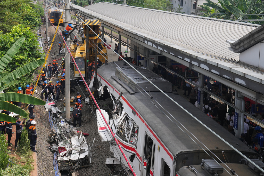 Workers use a heavy machine to remove the wreckage of a train after a collision in Bekasi, Indonesia, Tuesday, April 28, 2026. (AP Photo/Tatan Syuflana)