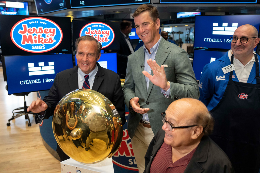 Jersey Mike's Subs' chairman of the board of directors Peter Cancro, left, and Eli Manning, right, pose with a ceremonial bell before the planned IPO of Jersey Mike's Subs on the floor of the New York Stock Exchange, Thursday, July 30, 2026, in New York. (AP Photo/Yuki Iwamura)
