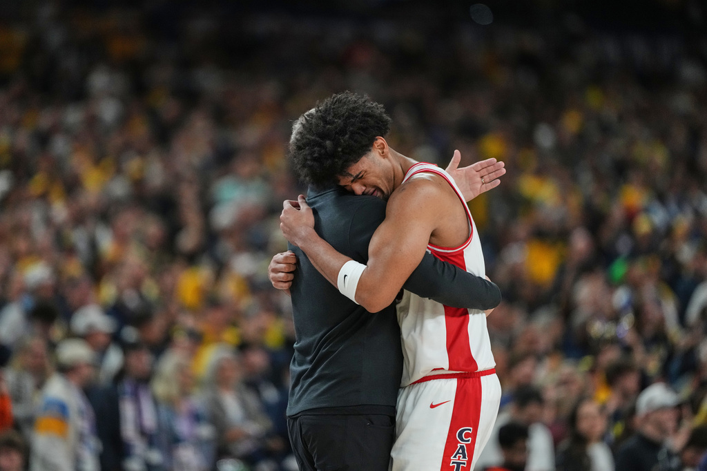 Arizona's Koa Peat, right, hugs head coach Tommy Lloyd near the end of an NCAA college basketball tournament semifinal game against Arizona at the Final Four, Saturday, April 4, 2026, in Indianapolis. (AP Photo/Michael Conroy)