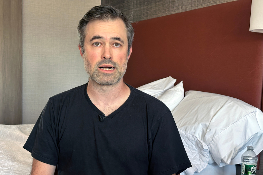 Mark Bray, a Rutgers assistant professor of history, waits in a hotel room in Newark, N.J., before a planned flight to Spain on Thursday, Oct. 9, 2025. (AP Photo/Ted Shaffrey)