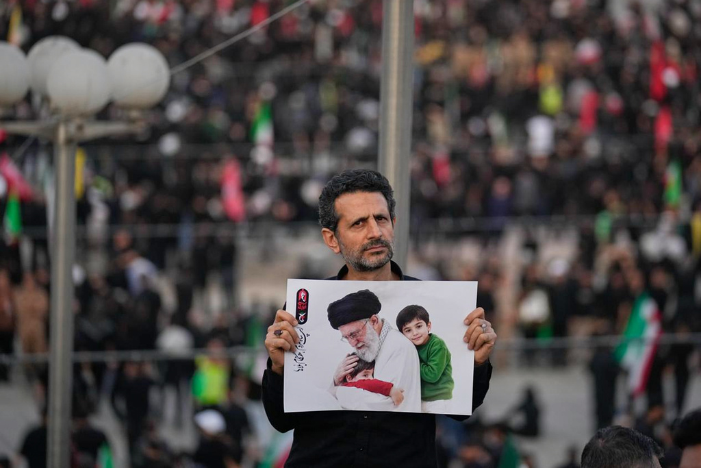 A man holds a picture of slain Iranian Supreme Leader Ayatollah Ali Khamenei as a crowd waits for his casket to arrive at the Imam Khomeini Mosalla Grand Mosque for the start of the dayslong funeral ceremonies in Tehran, Iran, Saturday, July 4, 2026. (AP Photo/Altaf Qadri)
