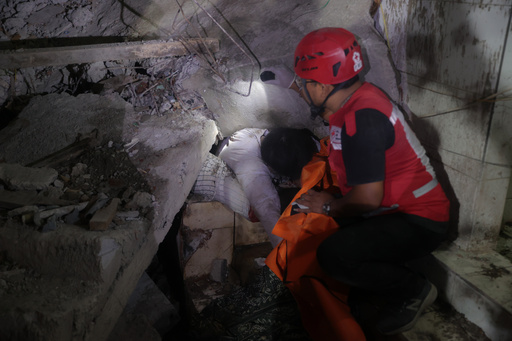 EDS NOTE: GRAPHIC CONTENT - A rescuer attempts to remove the trapped body of a victim after a building collapsed at an Islamic boarding school in Sidoarjo, East Java, Indonesia, Monday, Sept. 29, 2025. (AP Photo/Trisnadi) EDS NOTE: GRAPHIC CONTENT - A rescuer attempts to remove the trapped body of a victim after a building collapsed at an Islamic boarding school in Sidoarjo, East Java, Indonesia, Monday, Sept. 29, 2025. (AP Photo/Trisnadi)
